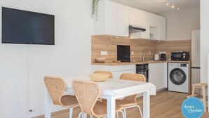 A modern kitchen with white cabinets, a wooden countertop, a built-in microwave, and a washing machine.