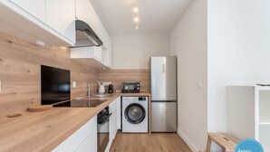 A compact kitchen with a washing machine, a microwave, and a refrigerator.