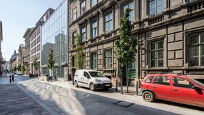 A street with parked cars and a building with large windows and a green door. - Spacious Stay at Bank Center   Parlament Neighbor (Budapest)
