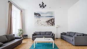 A modern living room with a grey sofa, a white coffee table, and a large beach-themed artwork on the wall. - Spacious Stay at Bank Center   Parlament Neighbor (Budapest)