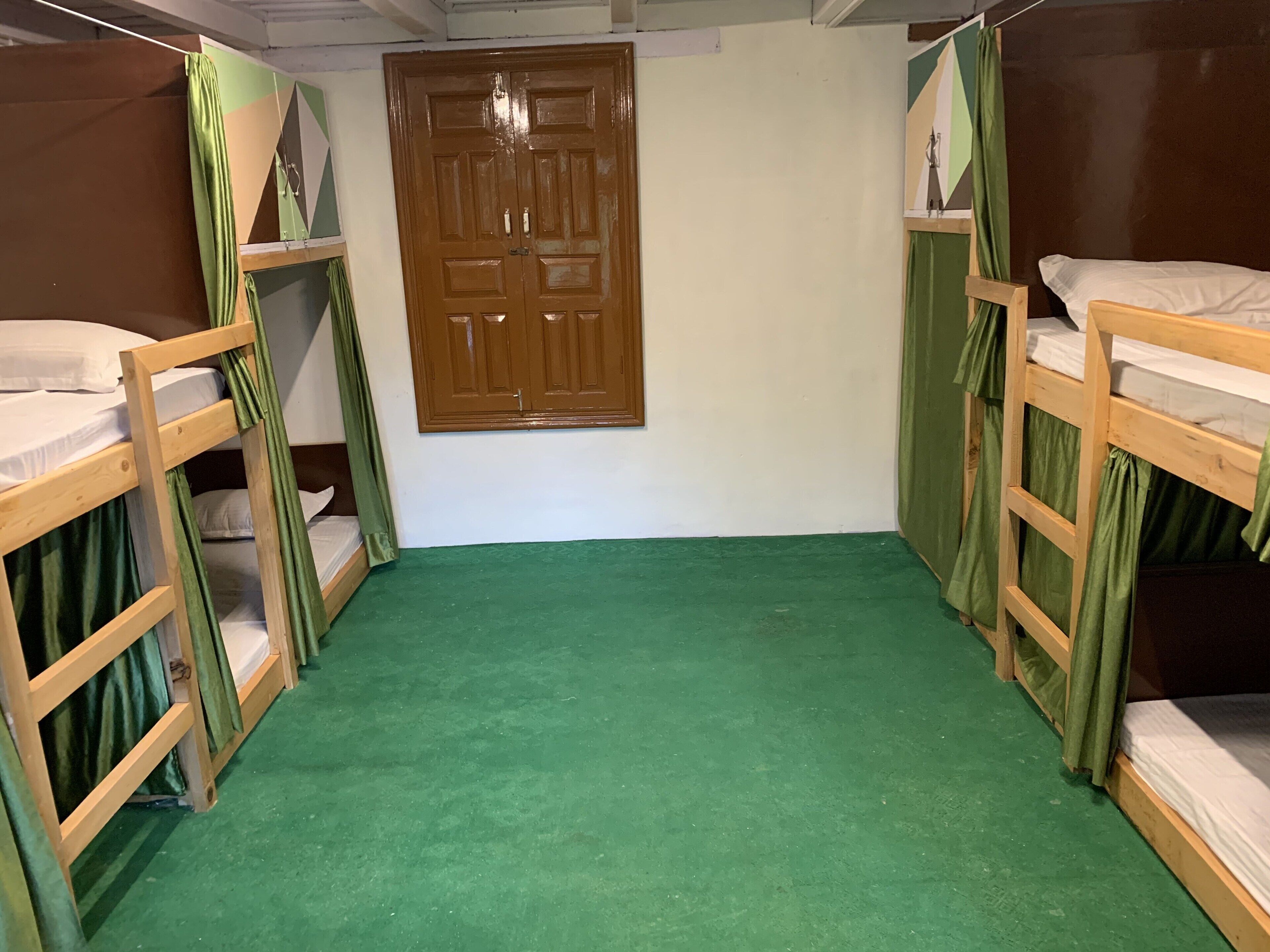 A room with bunk beds, a green carpet, and a wooden door.