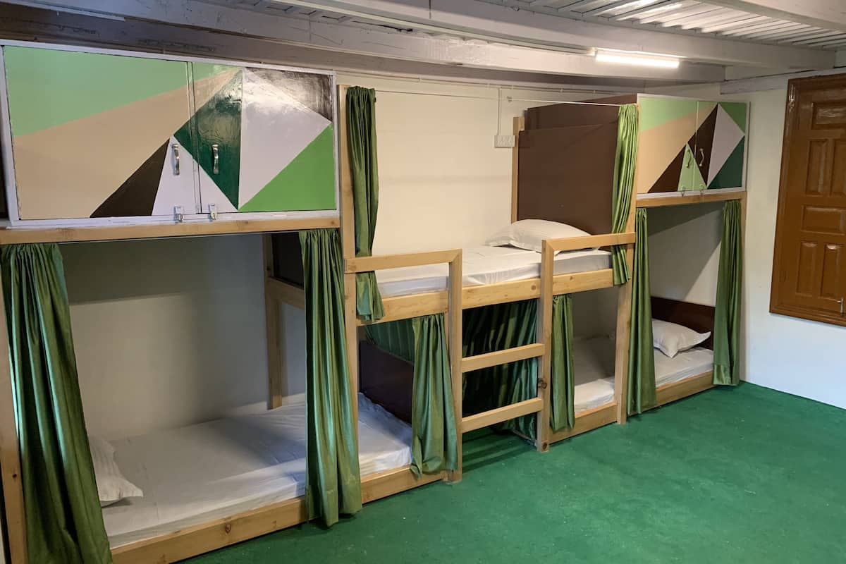 A room with bunk beds, green curtains, and a green carpet.