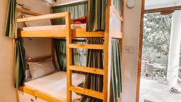 A bunk bed room with curtains, a window, and a door leading to an outdoor area.