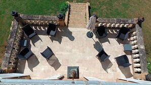 Un espace extérieur aménagé avec des sièges, accessible par des marches en pierre menant à une terrasse, le tout entouré de balustrades en pierre.