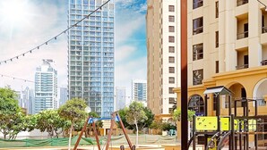 A modern building with a yellow facade, large windows, and a playground area with swings and a slide. - LUX The JBR BlueWaters View Suite 2 (Dubai)