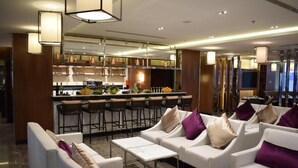 Un hall d’hôtel moderne avec des canapés blancs, un coin bar et une cuisine en arrière-plan.
