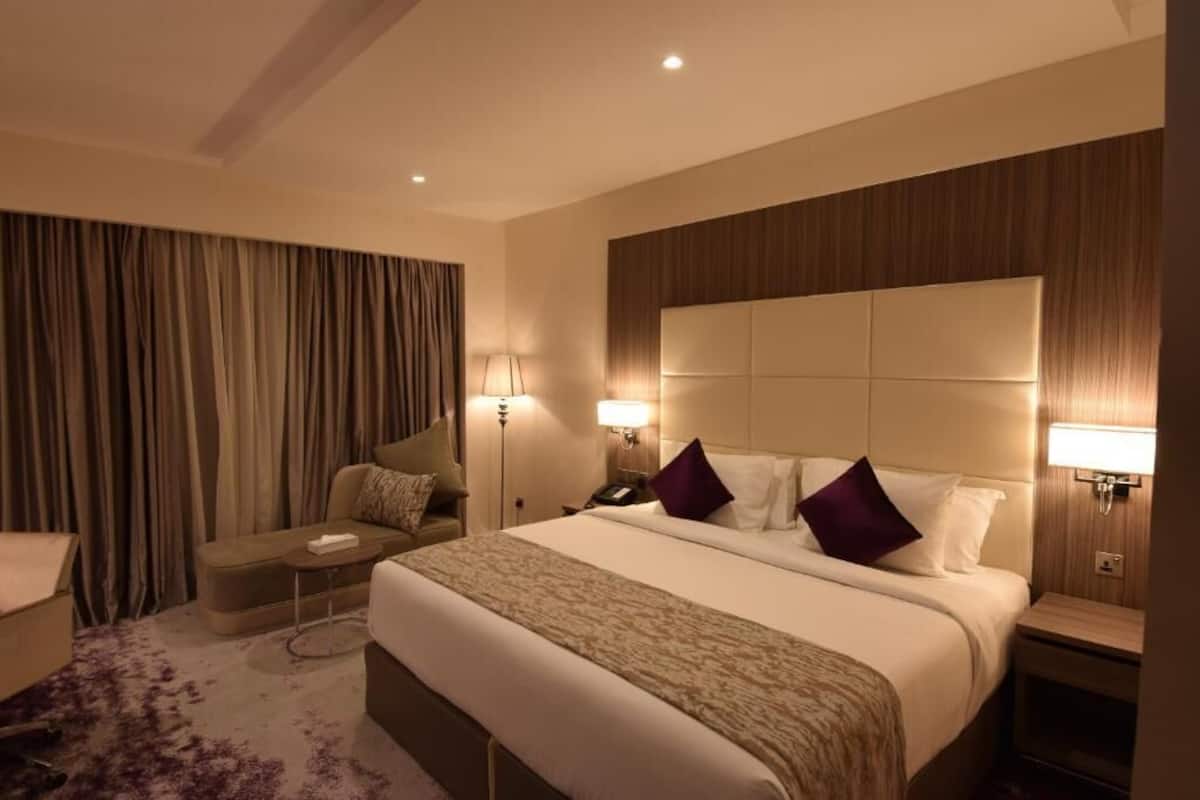 Een hotelkamer met een groot bed, een bank, een bijzettafeltje en een lamp.