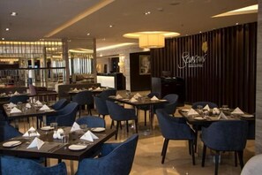 A restaurant with tables set for dining, a bar area, and a reception desk.