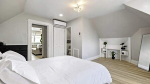 Une chambre avec un grand lit, une armoire, un bureau et une plante.