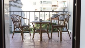 A balcony with two wicker chairs and a small table, overlooking a residential area with buildings and balconies. - Affittacamere Le Dimore del Riccio (Foggia)