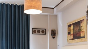 A hotel room with a bed, a chair, a hanging lamp, a painting, and a wall-mounted mask. - Affittacamere Le Dimore del Riccio (Foggia)