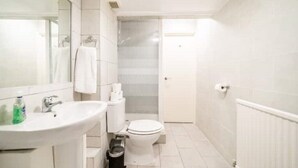 Un baño pequeño y limpio con lavamanos, inodoro y espejo.