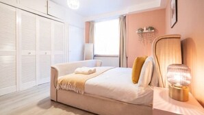 Un dormitorio con cama, mesita de noche, lámpara y armario.