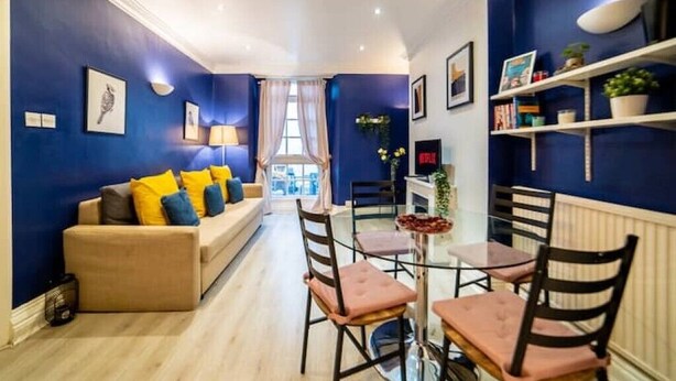 Una sala de estar moderna con un sofá, sillas y una mesa de comedor.