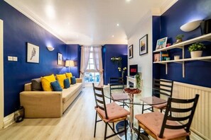 Ein modernes Wohnzimmer mit einer Couch, Sesseln und einem Esstisch.