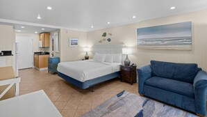 A bedroom with a bed, bedside tables, a couch, a painting, and a view of the ocean. - Oceanfront Views King Room with Amenities (Pawleys Island)