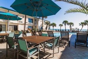 A poolside area with lounge chairs, umbrellas, and a view of the ocean. - Dunes King Room Oceanfront Views (Pawleys Island)