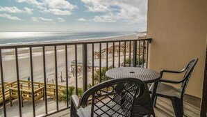 A balcony with a view of the beach, a table, and chairs. - Lavish 4th Floor Oceanfront King Room (Pawleys Island)