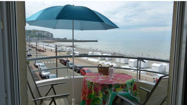 Enjoy breathtaking views of the beach and sea from this balcony, complete with a table and chairs under a shaded area.
