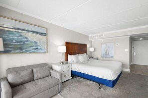 Une chambre d’hôtel avec un lit, un canapé, une table de chevet et un tableau au mur.