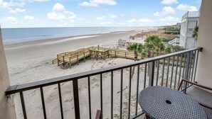 Un balcón con vista a una playa, terraza de madera y una silla.