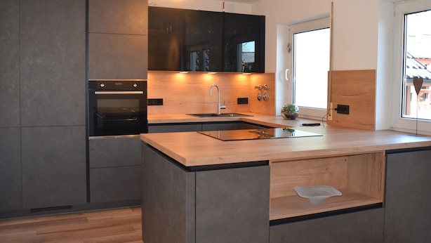 Een moderne keuken met een centraal eiland, een inbouwoven en een groot raam voor natuurlijk licht.