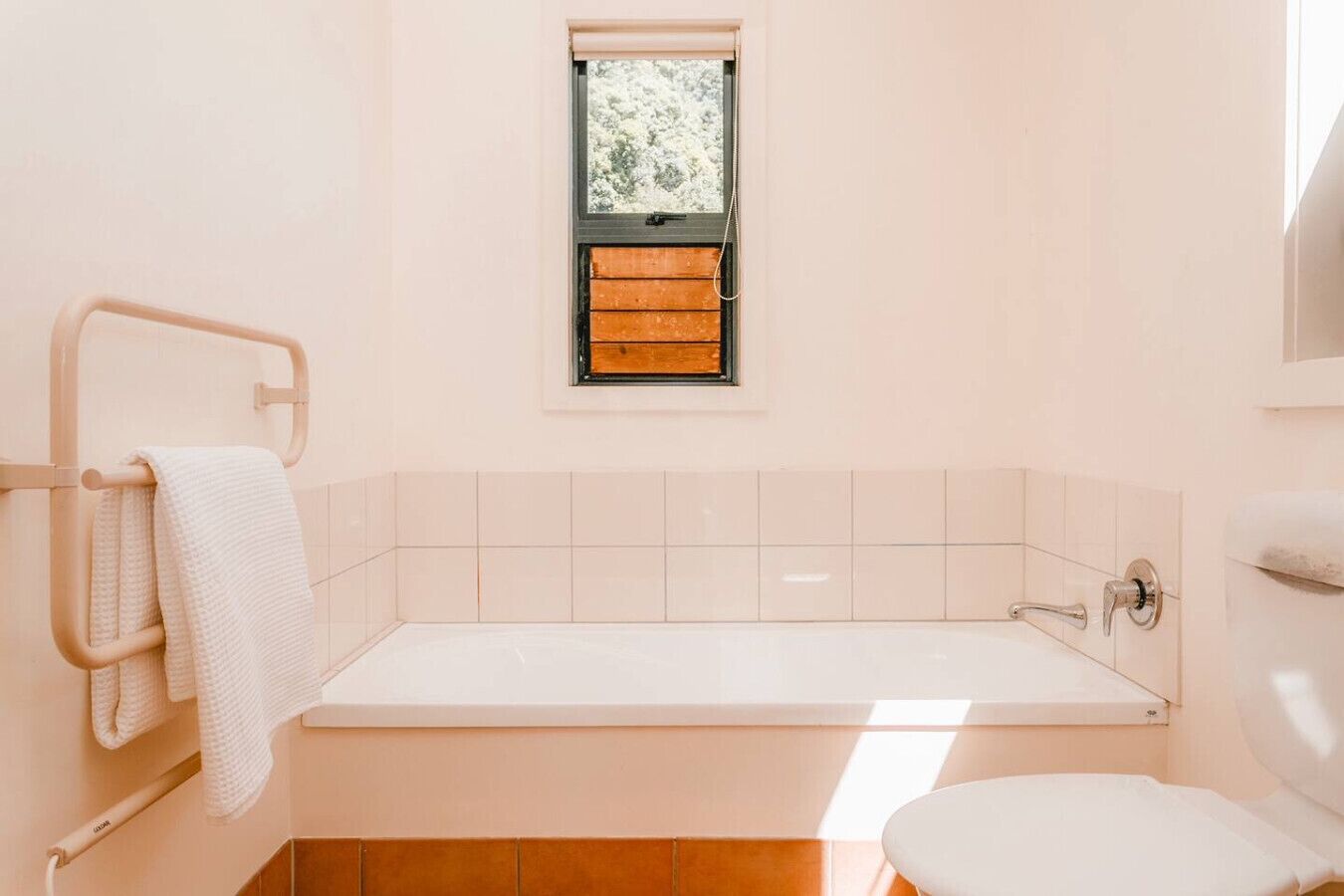 Et badeværelse med badekar, et vindue og et toilet.