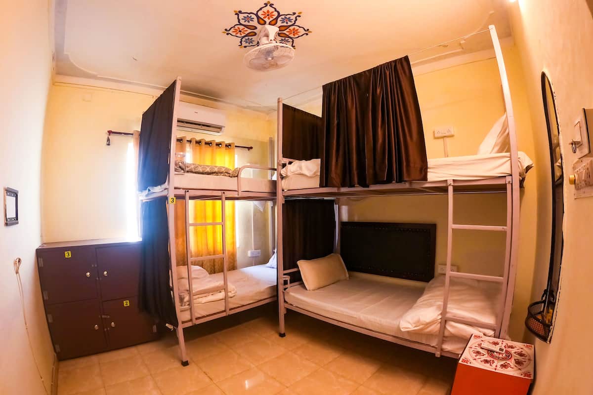Un dormitorio con camas literas, un armario, un equipo de aire acondicionado y un ventilador de techo.