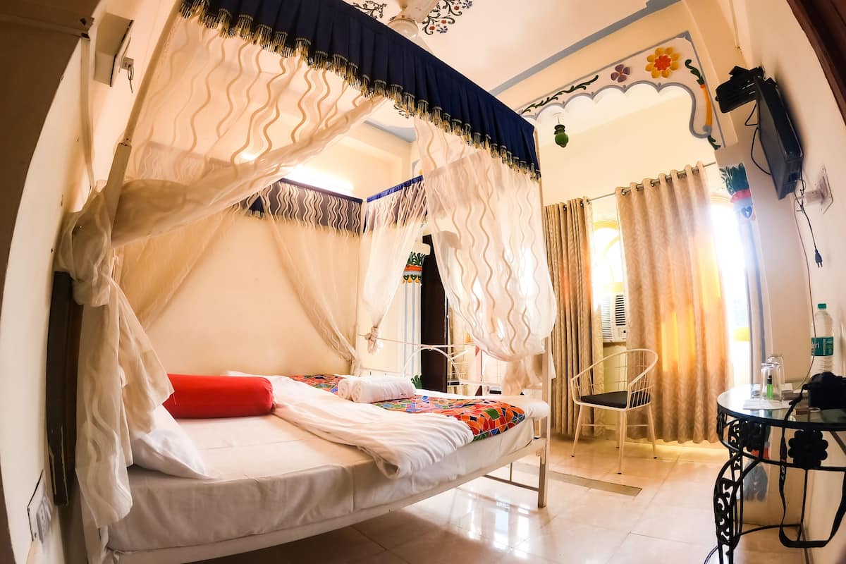 Una habitación con cama, una silla, una mesa y un techo decorativo.