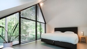 Une chambre à coucher moderne avec une grande fenêtre, un lit, une table de chevet et une plante en pot.
