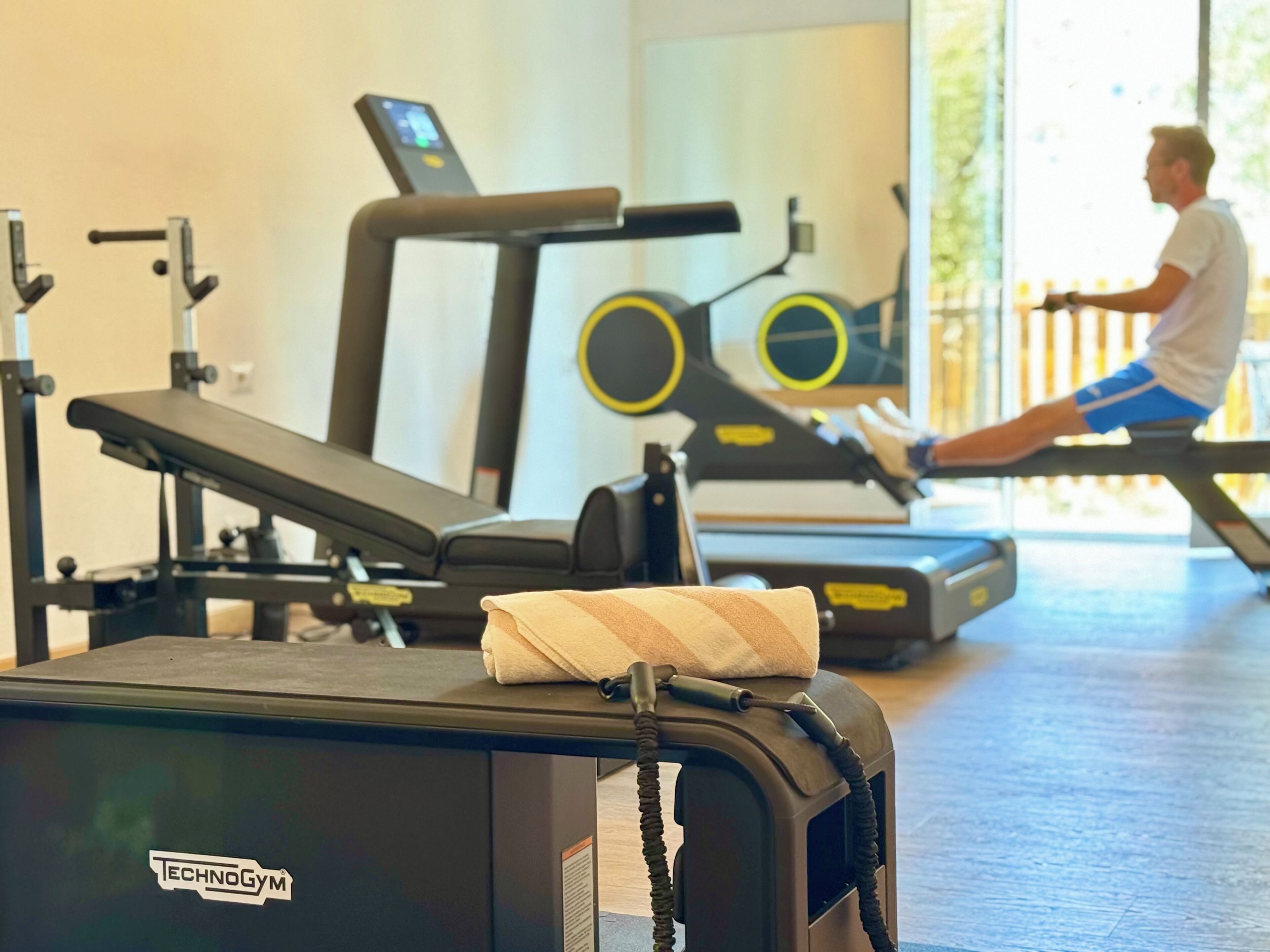 Ein Fitnessraum mit Trainingsgeräten, Laufband und einer Bank.