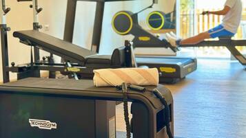 Ein Fitnessraum mit Trainingsgeräten, Laufband und einer Bank.