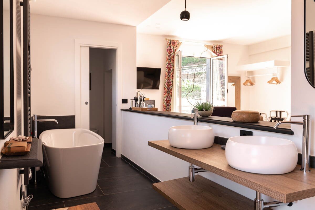 A modern bathroom with a freestanding bathtub, two sinks, and a large mirror.