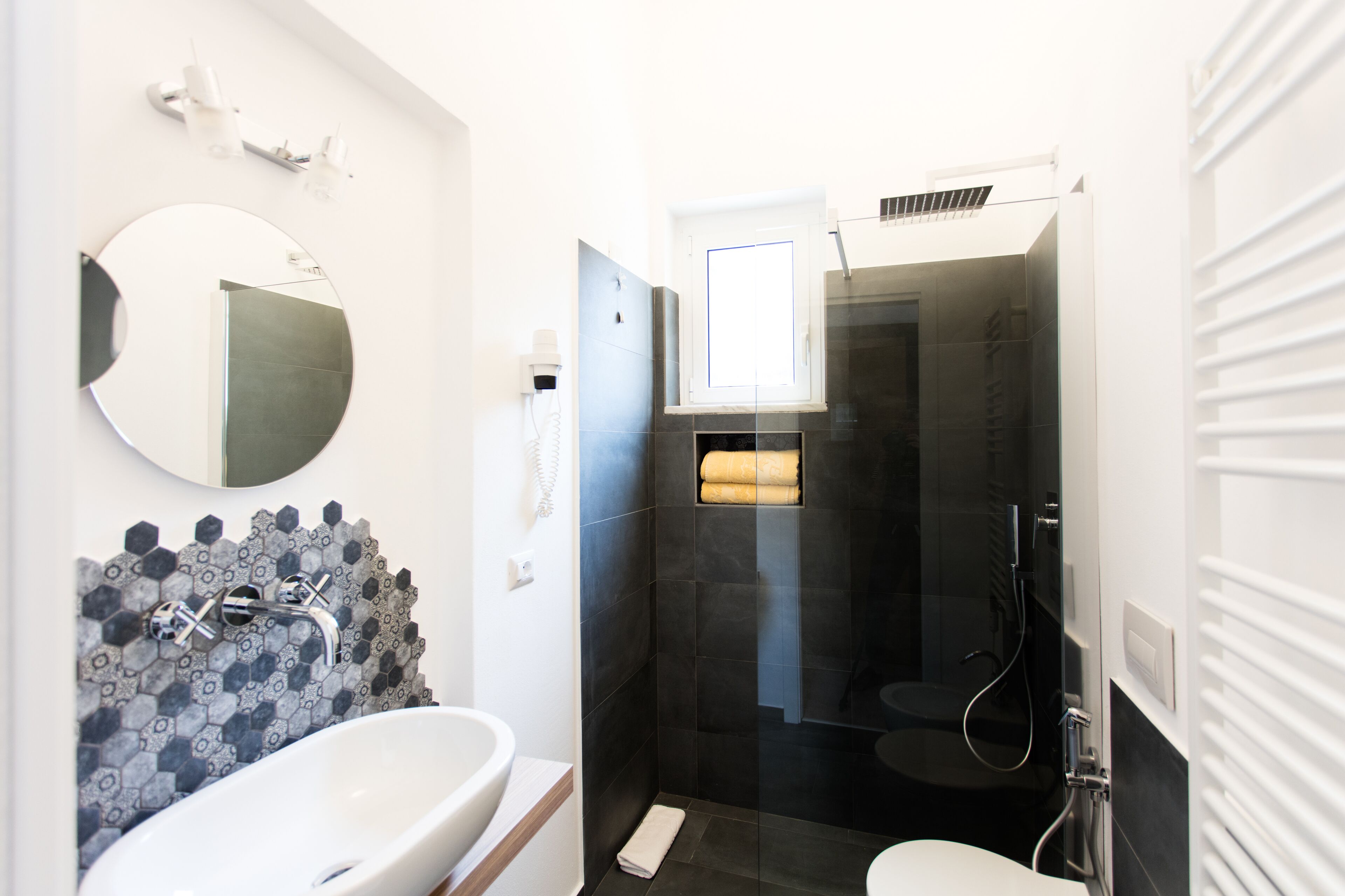 Une salle de bain moderne avec une baignoire sur pieds, un miroir rond et une douche à l’italienne.