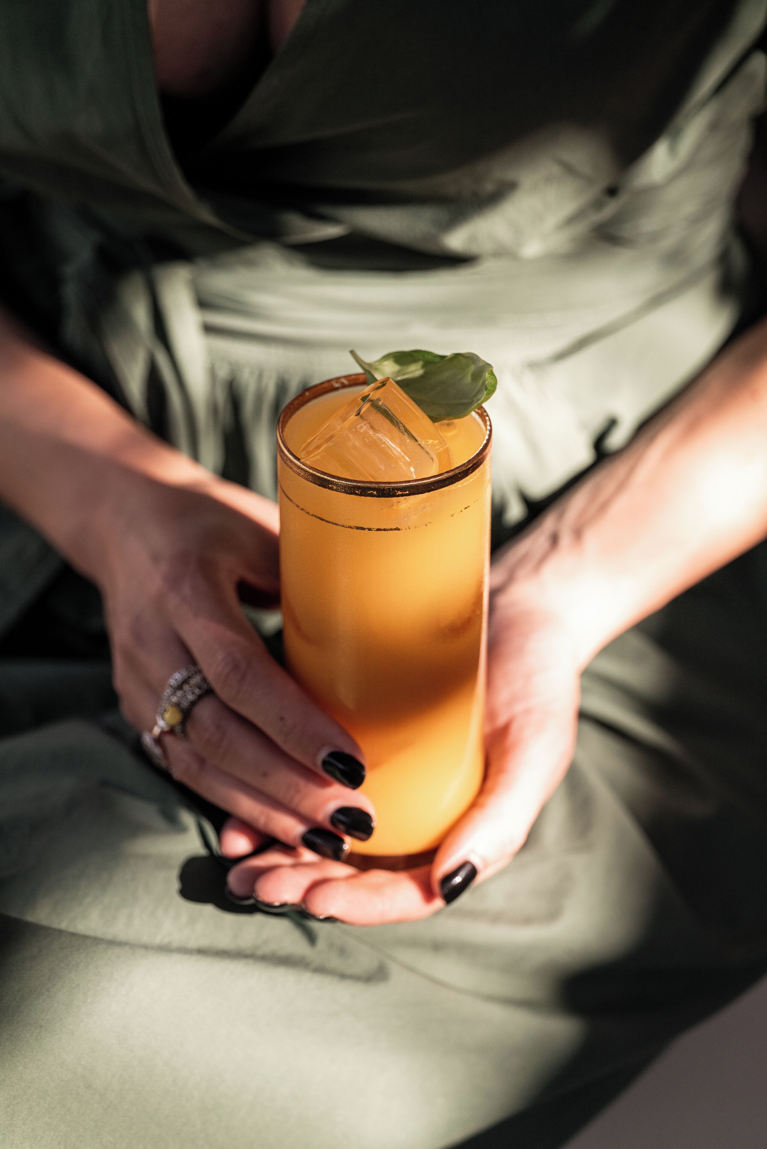A person holding a tall glass with a drink.
