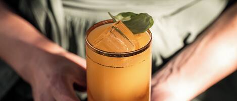 A person holding a tall glass with a drink.