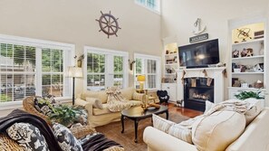 A spacious living room with a fireplace, a television, and a bookshelf.