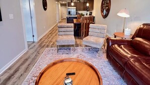 Un salón amplio con una mesa de centro de madera, un sofá de cuero marrón y una alfombra estampada.