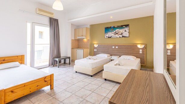 A hotel room with a large bed, two smaller beds, a desk, a chair, a kitchenette, and a balcony. - Simple Hotel Hersonissos Sun (Hersonissos)