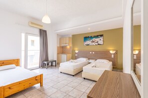A hotel room with a large bed, two smaller beds, a desk, a chair, a kitchenette, and a balcony. - Simple Hotel Hersonissos Sun (Hersonissos)
