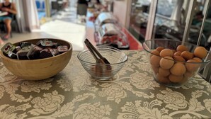 A table with a patterned tablecloth, a wooden bowl with packaged food, a clear glass bowl with a spoon, and a glass bowl with eggs. - Simple Hotel Hersonissos Sun (Hersonissos)