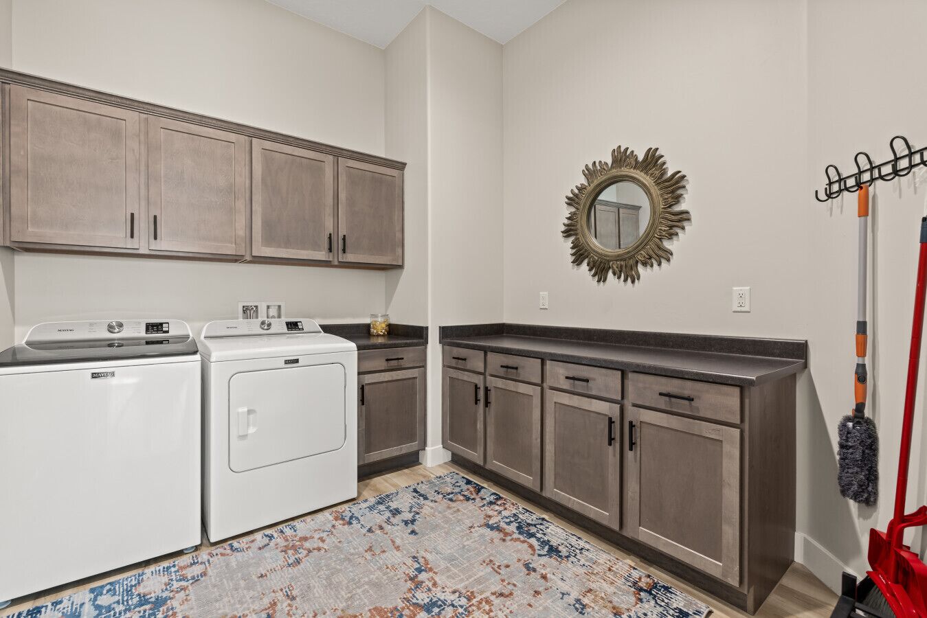 A laundry room with a washing machine, dryer, and a large mirror on the wall.