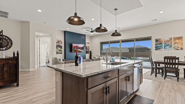 A modern kitchen with a large island, pendant lighting, and a view to the outside.