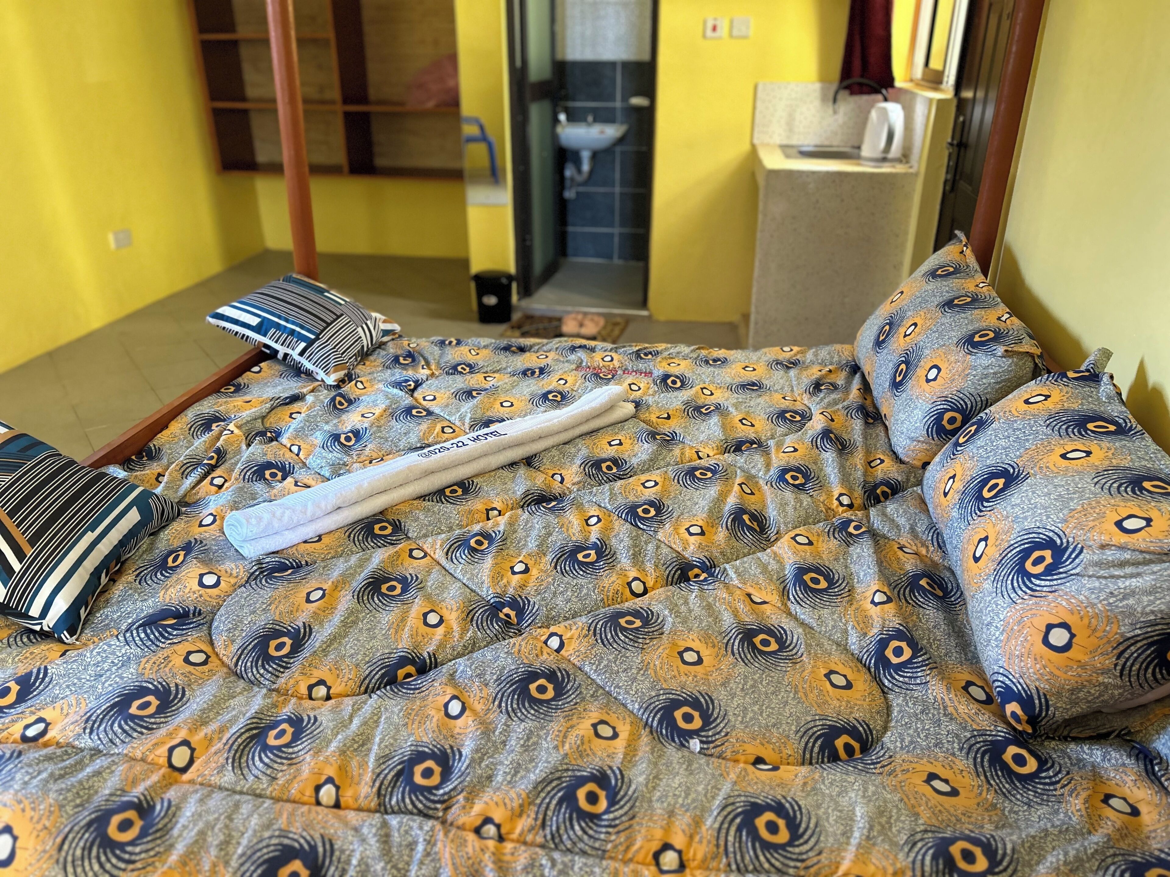A hotel room with a bed, pillows, and a bedside table.