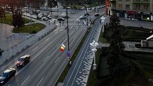 Une route à plusieurs voies, avec des véhicules, des passages piétons et un grand bâtiment doté d’un toit rouge et d’un dôme vert.