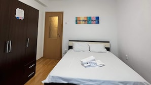 Une chambre à coucher avec un lit, une armoire, une porte et un tableau au mur.
