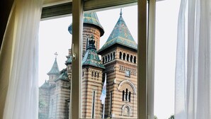 A room with a window overlooking a historic building with distinctive architecture. - Joy City Stay Victoriei 7G-3 (Timișoara)