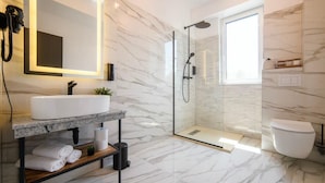 A modern bathroom with a marble floor, a glass-enclosed shower, a white sink, and a large mirror. - GBU Home - Olive Room (Timișoara)