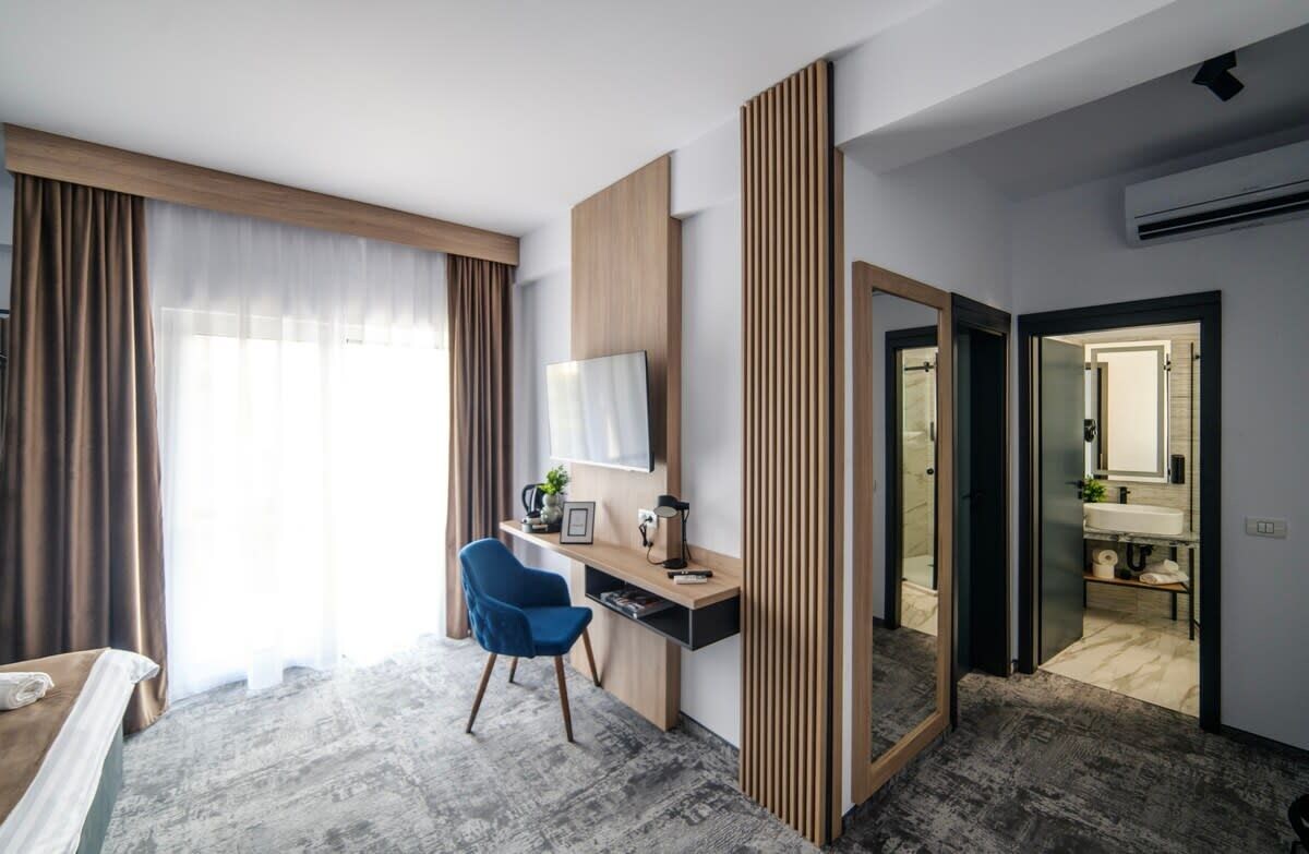 A modern hotel room with a desk, chair, and a large mirror.