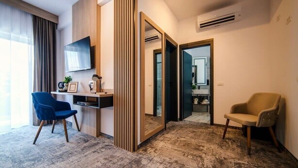 Een moderne hotelkamer met een grote spiegel, een bureau met stoel, een televisie en een kledingkast.